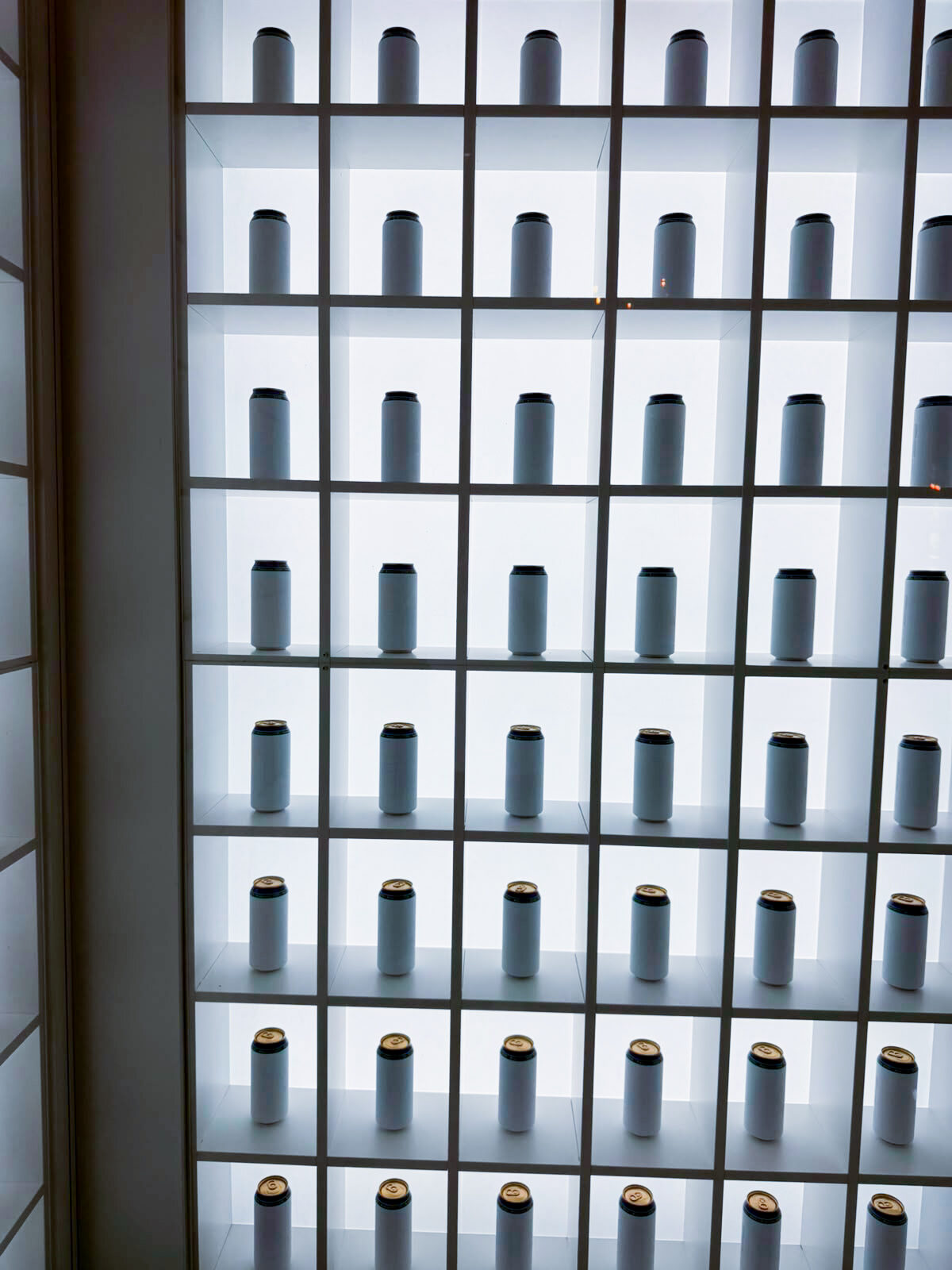 Finished cans presented in a lit display wall on site